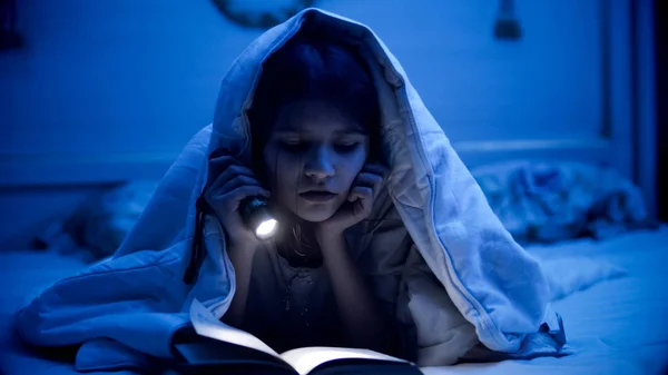 Retrato de adolescente acostada debajo de una manta y leyendo un libro — Foto de Stock