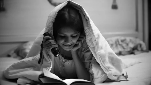 Portrait noir et blanc d'une adolescente souriante avec un livre de lecture de torche — Photo