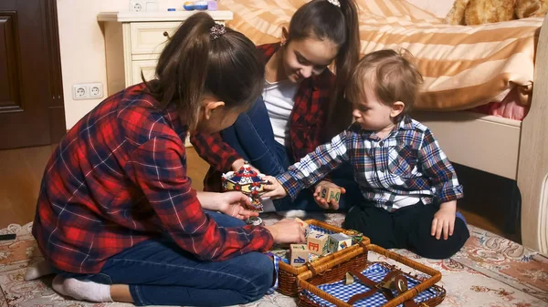 Glada leende tjejer leker med småbarn pojke hemma — Stockfoto