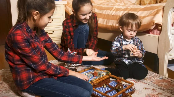 Två tonårsflickor med småbarn pojke leker på golvet vid sovrum — Stockfoto