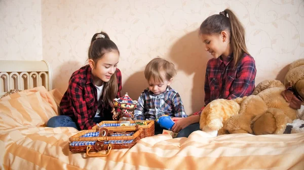 Дві усміхнені дівчата грають на ліжку з маленьким хлопчиком — стокове фото