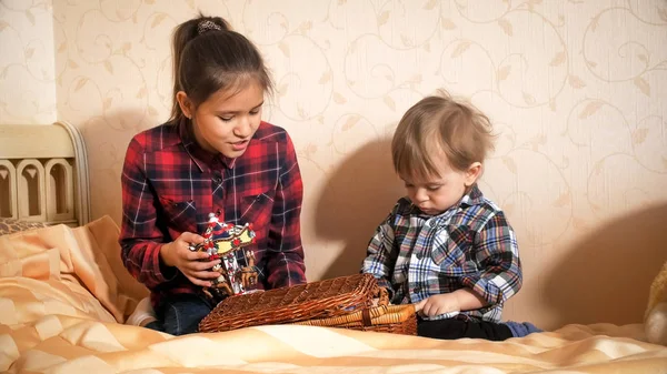 Adolescente jugando con su hermano pequeño en la cama en el dormitorio — Foto de Stock