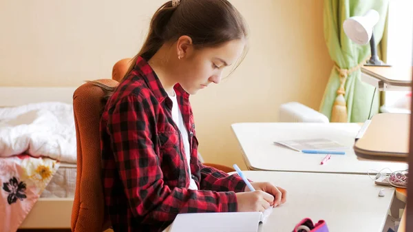 Portrait d'une adolescente faisant ses devoirs dans la chambre — Photo