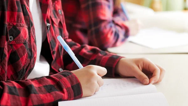 Foto de primer plano de la niña escribiendo tarea con pluma — Foto de Stock