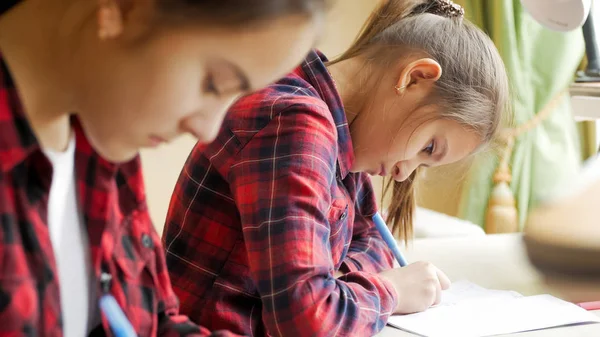 Porträt eines konzentrierten 10-jährigen Mädchens, das mit seiner Schwester Hausaufgaben macht — Stockfoto