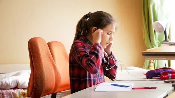 Ritratto di ragazza adolescente che ascolta musica con le cuffie mentre fa i compiti — Foto Stock