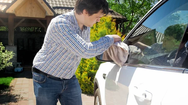 Kierowca-mężczyzna Yougn czyszczenia samochodu lustro szmatą — Zdjęcie stockowe
