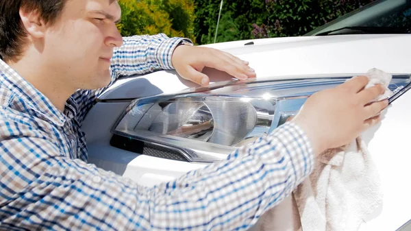 Foto de primer plano del joven pulido faros de coche con tela —  Fotos de Stock