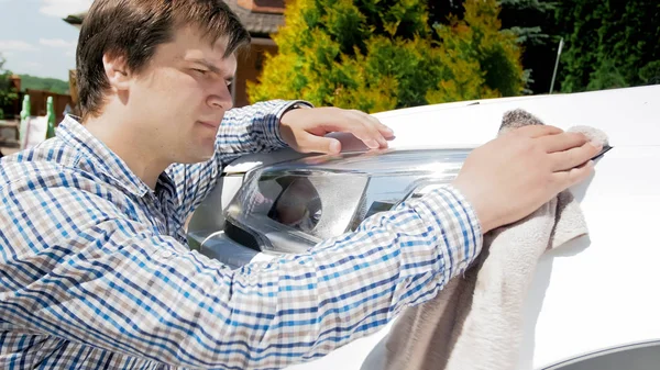 Handsome young man polishing car headlamps with cloth — Stock Photo, Image