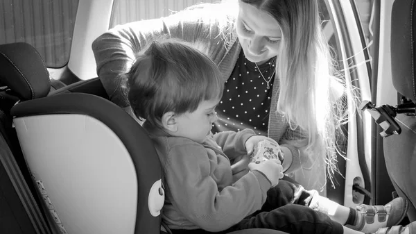 Imagen en blanco y negro de la madre sujetando los cinturones de seguridad de los niños del coche — Foto de Stock