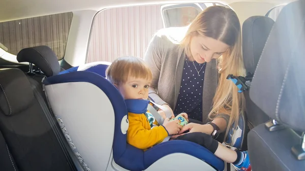 Retrato de una hermosa mujer sonriente con su hijo pequeño en asiento de seguridad — Foto de Stock