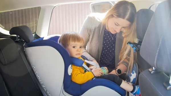 Retrato de la madre joven cinturones de sujeción y hebilla de coche asiento de seguridad para niños —  Fotos de Stock