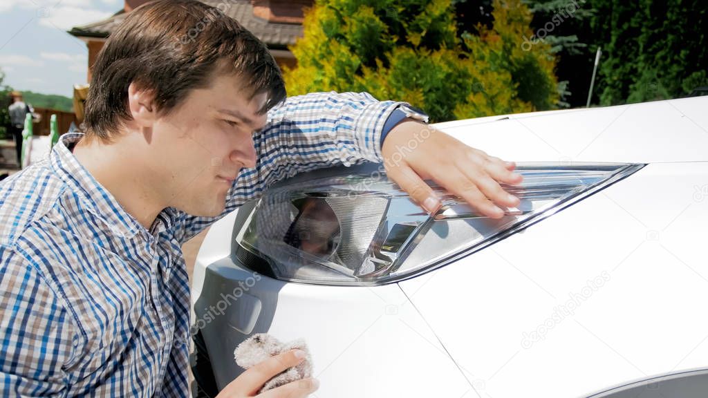 Closeup portrait of young man washing car headlights