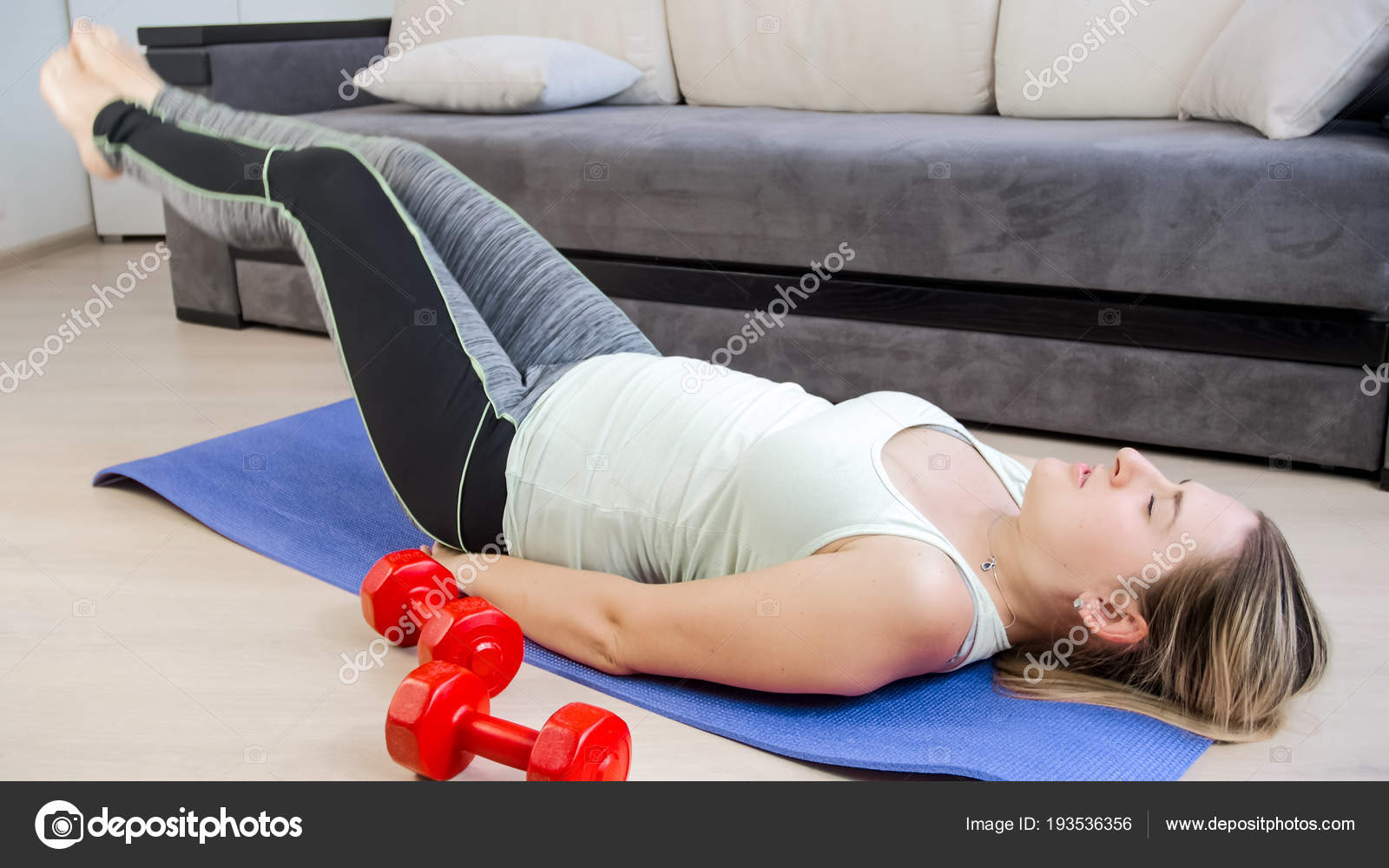 Young Woman Lying On Floor At Home And Doing Abs Crunches And