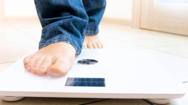 Closeup photo of barefoot person stepping on electronic scales clipart