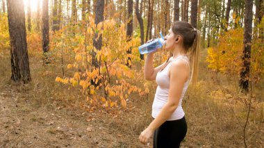 Ormanda koşu sırasında genç sportif kadın içme suyu portresi
