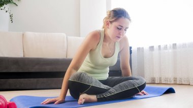 Genç kadın fitness mat oturma odasında egzersiz sonra yorgun hissediyorum