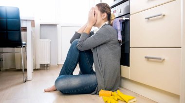 Yerde ağlıyor ve yüz eller ile kapanış ev hanımı genç yorgun