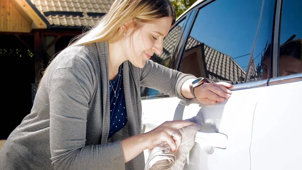 Bella donna sorridente pulire la sua auto con un panno — Foto Stock