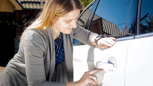 Portrait of smiling young woman polishing her car door handles — Stock Photo, Image