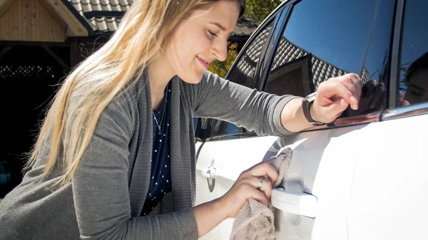 Beautiful young blonde woman cleaning her car — Stock Photo, Image