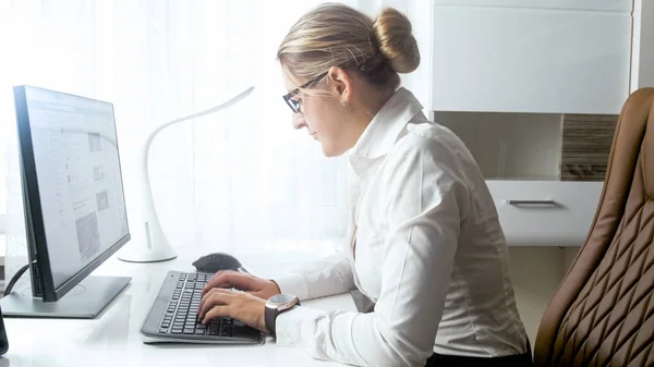 Porträt einer jungen Geschäftsfrau, die E-Mail-Nachrichten auf dem Computer tippt — Stockfoto