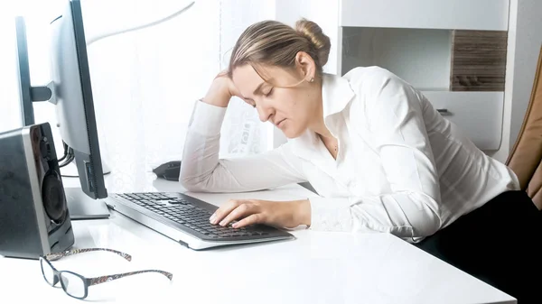 Portrait of tired young woman sleeping on working desk at office — Stock Photo, Image