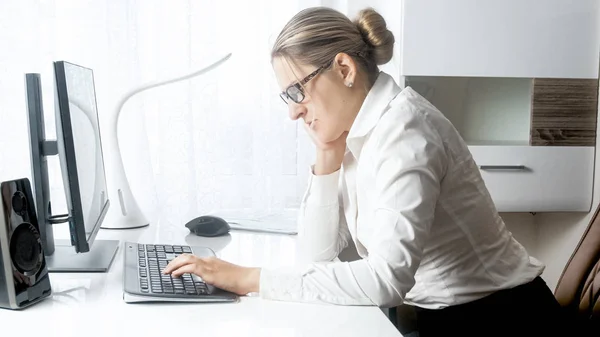 Porträt einer gestressten Geschäftsfrau, die im Büro am Computer arbeitet — Stockfoto