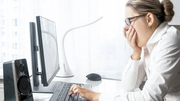 Portrait of young tired businesswoman yawning while working at office — Stock Photo, Image