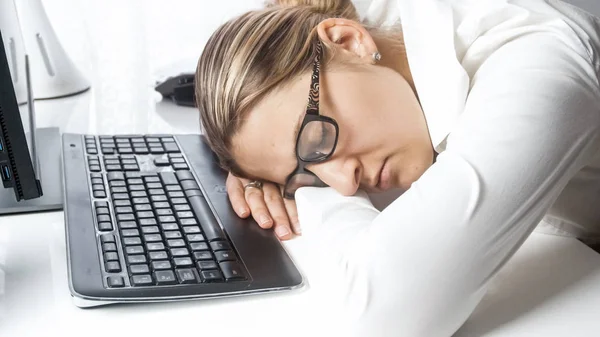 Closeup portrait of tired businesswoman lying on computer keyboard at office — Stock Photo, Image