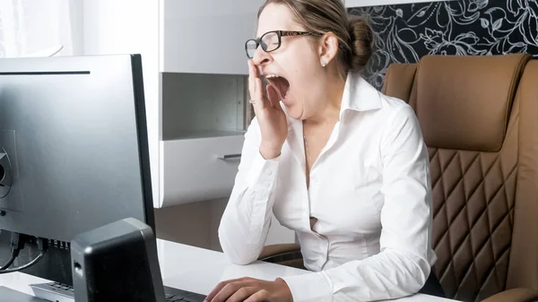 Portrait of tired young woman yawning in office — Stock Photo, Image