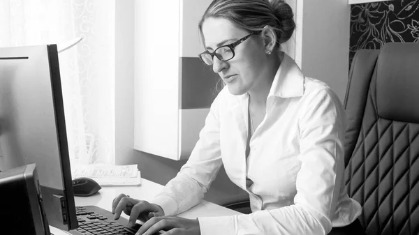 Black and white portrait of young secretary working on computer at office — Stock Photo, Image