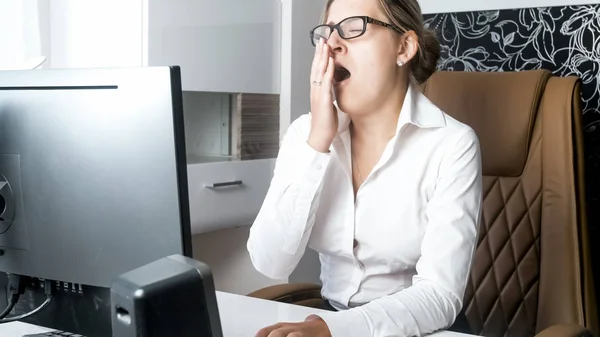 Retrato de una joven agotada sintiéndose somnolienta y bostezando en la oficina — Foto de Stock