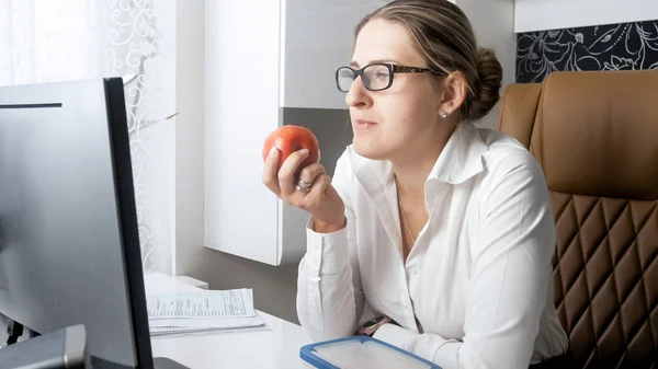 Portret van de jonge vrouw rode appel eten tijdens pauze op kantoor — Stockfoto