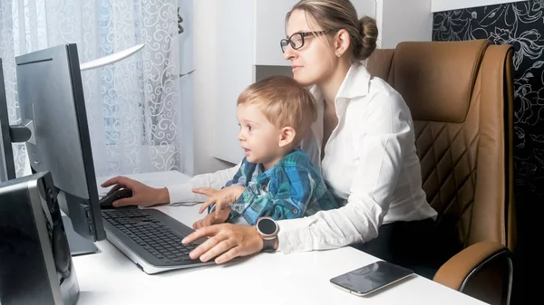 Vacker ung affärskvinna arbetar med sonen småbarn i office — Stockfoto