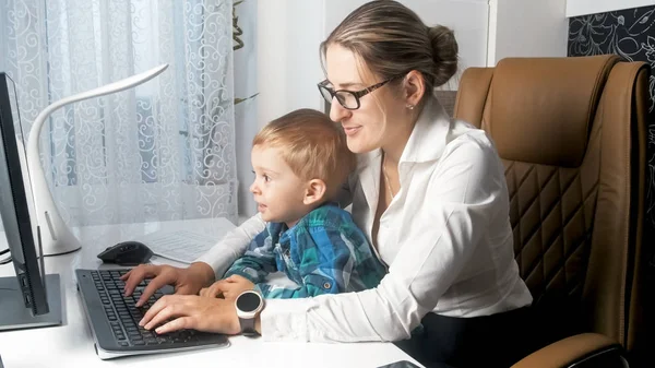 Bela jovem empresária trabalhando no computador com seu menino de 2 anos — Fotografia de Stock