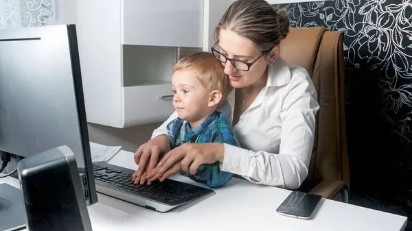 Retrato de jovem empresária ensinando seu menino usando computador no escritório — Fotografia de Stock