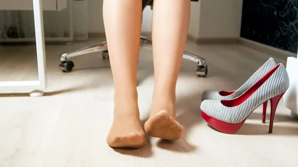 Jovem mulher em meia-calça em movimento pés cansados e dedos dos pés após o dia de trabalho no escritório — Fotografia de Stock