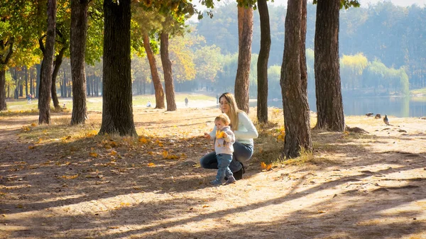 Beautiful young woman with her 1 year old baby boy in autumn park — Stock Photo, Image