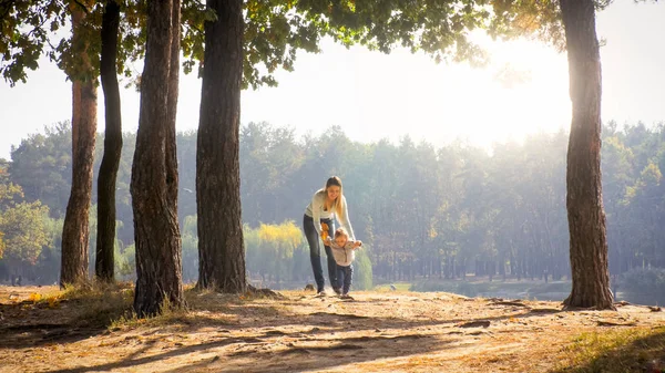 Beautiful young woman walking with her toddler son at autumn park — Stock Photo, Image