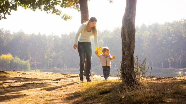 Hermosa madre sonriente con hijo pequeño caminando en el parque en el día soleado —  Fotos de Stock