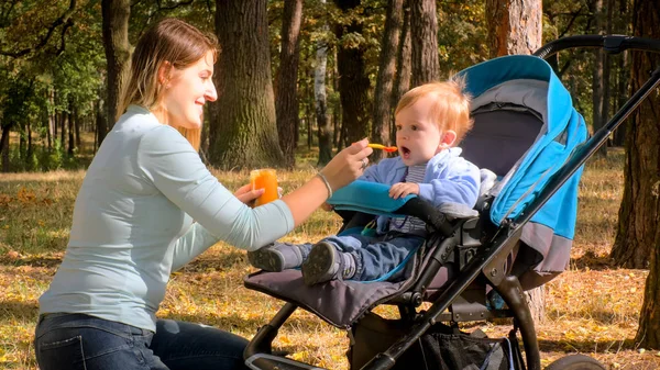 Porträtt av söt småbarn pojke sitter i barnvagnen och äta gröt — Stockfoto