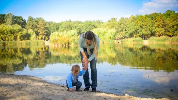 Ładny toddler chłopiec z młoda matka w pobliżu lake Park — Zdjęcie stockowe