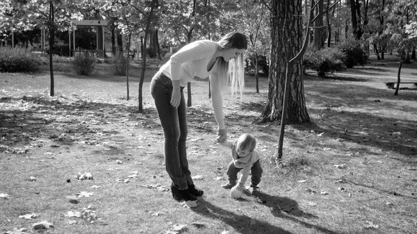 Black and white photo of young mother playing in park with her toddler son — Stock Photo, Image