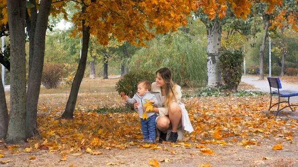 Happy smiling woman with 1 year old toddler boy at autumn park — Stock Photo, Image
