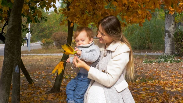 Portret van lachende jonge moeder haar peuter jongen in herfst park huggin — Stockfoto