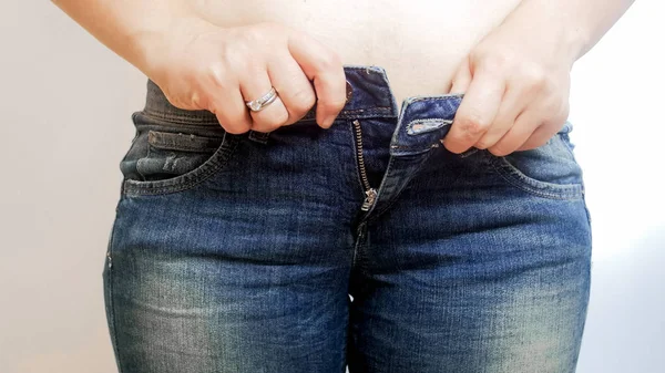 Крупним планом фото молодої жінки, яка бореться з жорсткими джинсами — стокове фото