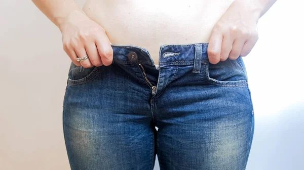 Foto de primer plano de una mujer joven con sobrepeso que lucha usando jeans ajustados — Foto de Stock