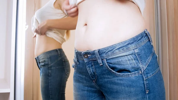 Schöne junge Frau mit perfektem Bauch trägt Jeans am großen Spiegel — Stockfoto