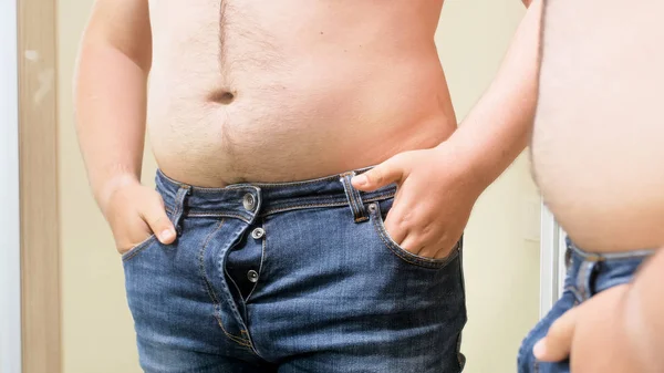 Jovem com grande barriga gorda lutando para usar jeans apertados — Fotografia de Stock